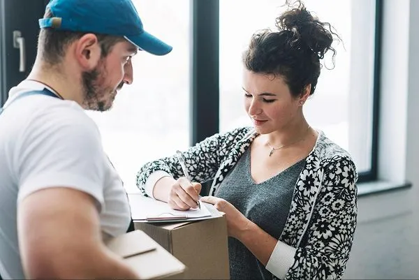 A woman signing on her delivery package.